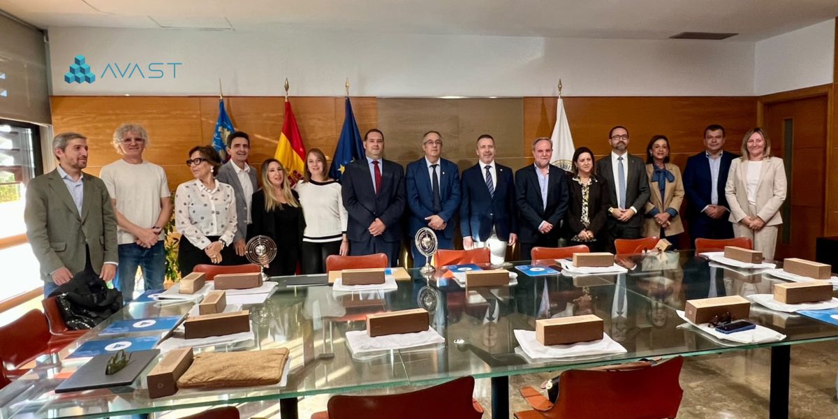 Fotografía de grupo de los asistentes a una reunión institucional y académica en una sala de juntas con una mesa de cristal en primer plano.